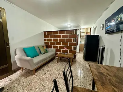 a living room with a couch and a brick wall at Cómodo en zona residencial a 1m de Av. el poblado in Envigado
