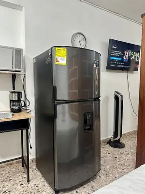 a refrigerator in a room with a clock on the wall at Cómodo en zona residencial a 1m de Av. el poblado in Envigado