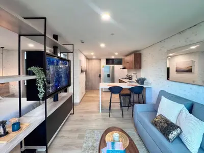 a living room with a blue couch and a kitchen at 1BR AC Near Unicentro, UPB & Parques Laureles in Medellín
