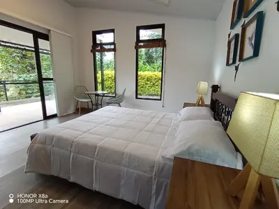 a bedroom with a large white bed and windows at Hospedaje Campestre Providencia in Manizales