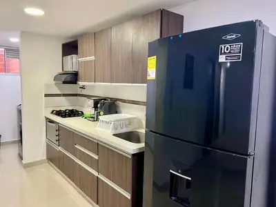 a kitchen with a black refrigerator and wooden cabinets at Luxury 3BR Apartment in the heart of Medellin in Medellín