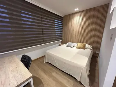 a bedroom with a bed and a table and a window at Lujoso Apartamento a Pasos del Metro de Medellin in Medellín