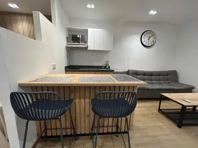 a kitchen with a bar with two chairs and a couch at Lujoso Apartamento a Pasos del Metro de Medellin in Medellín