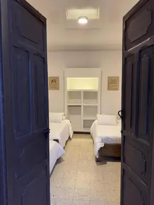 a room with two beds with white sheets and a door at Vivienda turística Casa Rionegro colonial in Rionegro
