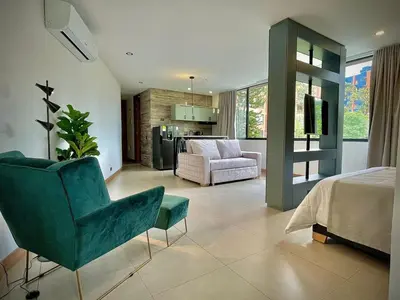 a living room with a green chair and a bedroom at Nice Apartment 205 in san lucas in Medellín