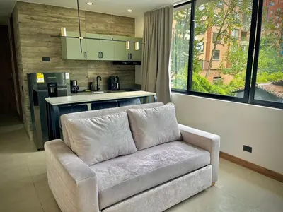 a living room with a couch and a kitchen at Nice Apartment 205 in san lucas in Medellín