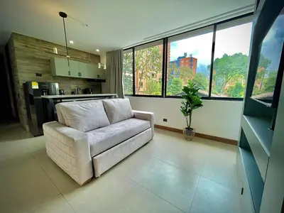a living room with a white couch and some windows at Nice Apartment 205 in san lucas in Medellín