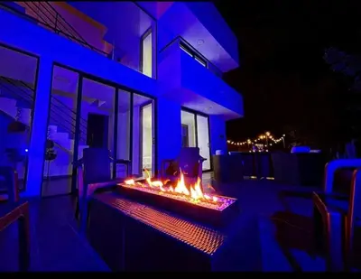 a fire pit on the side of a house at night at Villa cerca al aeropuerto in Guarne