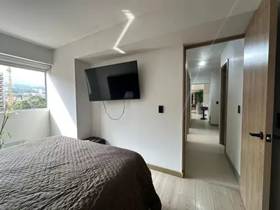 a bedroom with a bed and a flat screen tv on the wall at apartamento familiar de 3 habitaciones por meses in La Estrella