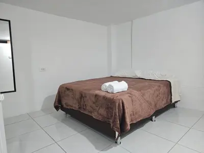 a bed in a white room with a brown blanket at KaVal in Jardin