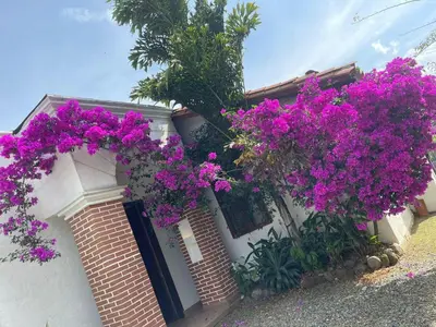 a house with purple flowers on the side of it at Casa colonial hermosa divisa a 1 45 h de Medellin in Venecia