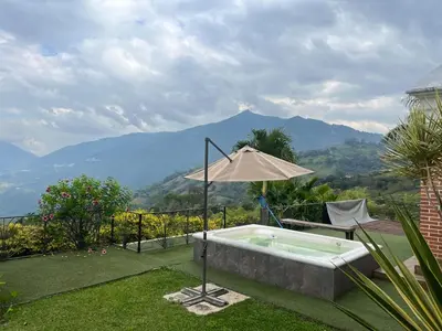 a hot tub with an umbrella in the grass at Casa colonial hermosa divisa a 1 45 h de Medellin in Venecia
