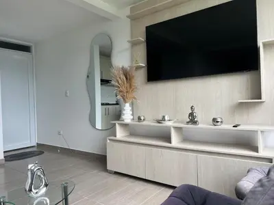a living room with a flat screen tv on a wall at Apartamento TERMINAL DE TRANSPORTE, CABLE AEREO, DOLLARCITY, D1 in Manizales