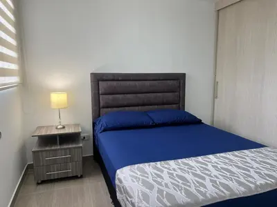 a bedroom with a blue bed and a nightstand with a lamp at Apartamento TERMINAL DE TRANSPORTE, CABLE AEREO, DOLLARCITY, D1 in Manizales