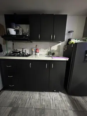 a kitchen with black cabinets and a sink and a refrigerator at Apartamento alto de palmas 1 in Medellín