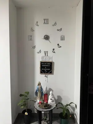 a clock on a wall with a table and plants at Apartamento alto de palmas 1 in Medellín