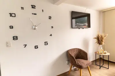 a room with a chair and a clock on the wall at Apartamento via TERMALES Y LOS NEVADOS in Manizales