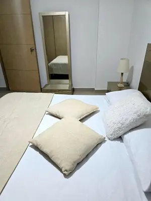 a white bed with two pillows on top of it at Cálido y moderno lugar Sabaneta in Sabaneta