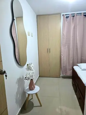 a bedroom with a mirror and a vase of flowers on a table at Cálido y moderno lugar Sabaneta in Sabaneta