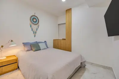 a white bedroom with a bed and a night stand at Opulent and Luxury 4 Bedroom in Sabaneta