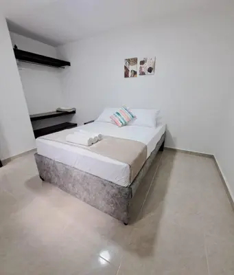 a bed in a room with a white wall at Casa del Sol in Mariquita