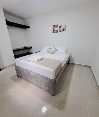 a white bed in a room with a white wall at Casa del Sol in Mariquita
