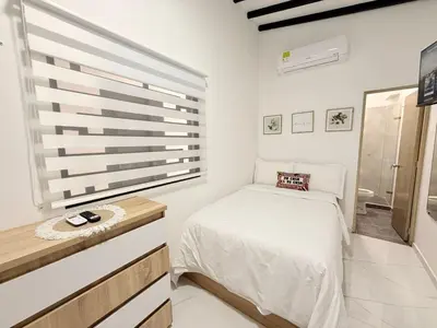 a white bedroom with a bed and a window at Aparta estudio 204 - Casa Bendita in Medellín
