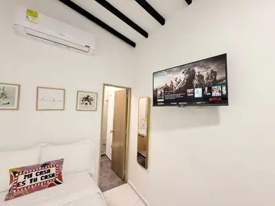 a living room with a white couch and a tv on the wall at Aparta estudio 204 - Casa Bendita in Medellín