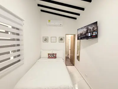 a white room with a bed and a flat screen tv at Aparta estudio 204 - Casa Bendita in Medellín