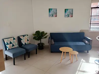 a living room with a blue couch and two chairs at Excelente Ubicación en La 70-Laureles in Medellín