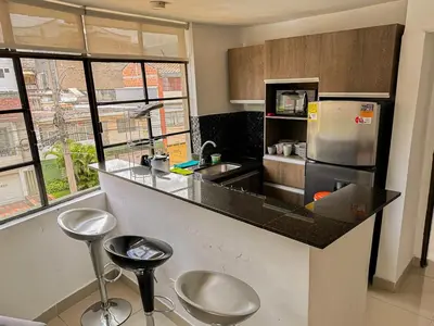 a kitchen with a counter with stools and a refrigerator at Excelente Ubicación en La 70-Laureles in Medellín