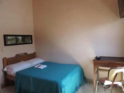 a small bedroom with a bed and a desk at Hotel La Casona Ituango in Ituango
