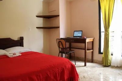 a bedroom with a bed and a desk with a laptop at Hotel La Casona Ituango in Ituango
