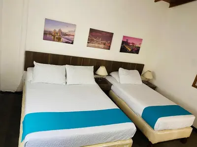 two beds in a small room with pictures on the wall at Hotel Confort LaCeja in La Ceja