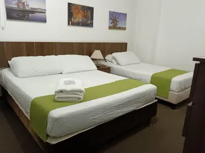 two beds with green and white sheets in a room at Hotel Confort LaCeja in La Ceja