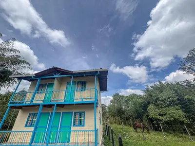 a blue and white house with a horse in a field at Las Casas de Tomate in Guatapé