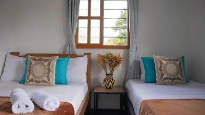 two beds in a room with a window at Las Casas de Tomate in Guatapé