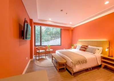 a bedroom with orange walls and a bed and a table at Contemporary Space Steps from El Tesoro 305 in Medellín
