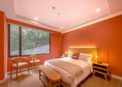 a bedroom with orange walls and a bed and a window at Contemporary Space Steps from El Tesoro 305 in Medellín