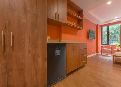 a kitchen with orange walls and wooden cabinets at Contemporary Space Steps from El Tesoro 305 in Medellín