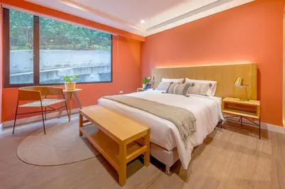 a bedroom with orange walls and a bed and a table at El Tesoro Escape Modern & Cozy Room 303 in Medellín