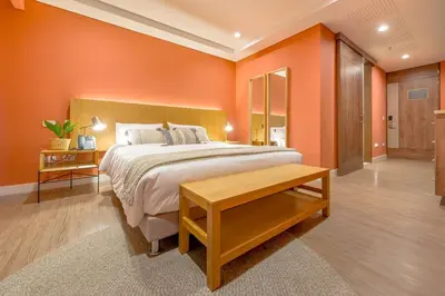 a bedroom with a large bed with orange walls at El Tesoro Escape Modern & Cozy Room 303 in Medellín