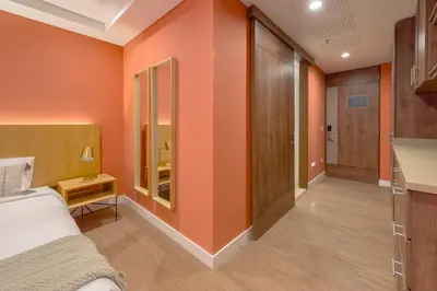 a bedroom with orange walls and a bed and a table at El Tesoro Escape Modern & Cozy Room 303 in Medellín