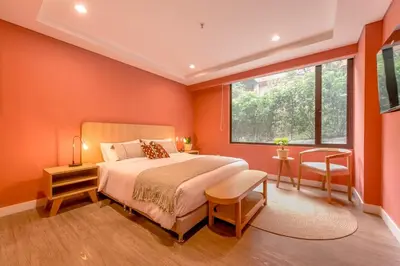 a bedroom with orange walls and a bed and a window at Room Modern Elegance Just Steps from El Tesoro 306 in Medellín