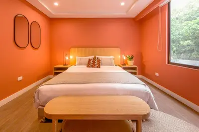 a bedroom with a large bed with orange walls at Room Modern Elegance Just Steps from El Tesoro 306 in Medellín