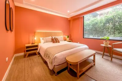 a bedroom with orange walls and a bed with a window at Room Modern Elegance Just Steps from El Tesoro 306 in Medellín