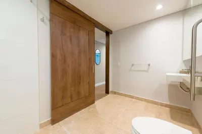 a bathroom with a toilet and a wooden door at Vibrant Space- Explore Wonders in El Tesoro 313 in Medellín
