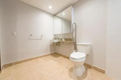 a white bathroom with a toilet and a mirror at Vibrant Space- Explore Wonders in El Tesoro 313 in Medellín