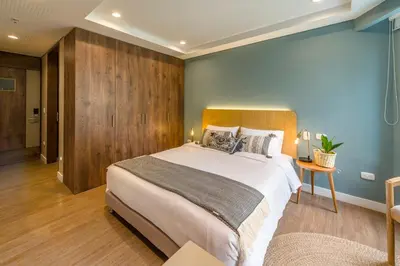a bedroom with a large bed and a blue wall at El Tesoro Stylish Escape - Urban Vibes 312 in Medellín
