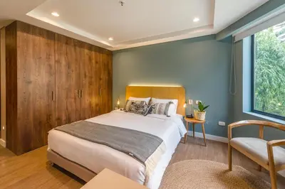 a bedroom with a large bed and a chair at El Tesoro Stylish Escape - Urban Vibes 312 in Medellín
